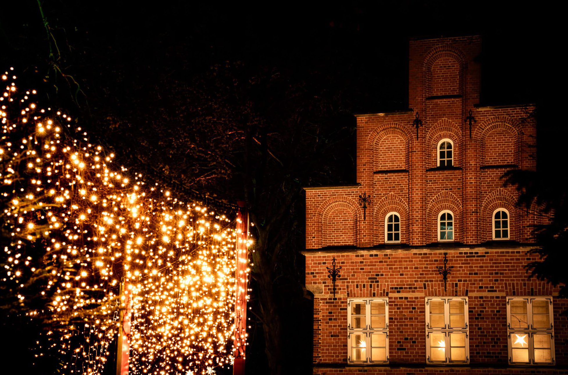 Ein beleuchtetes Gebäude und ein Vorhang aus Lichtern bei Nacht.