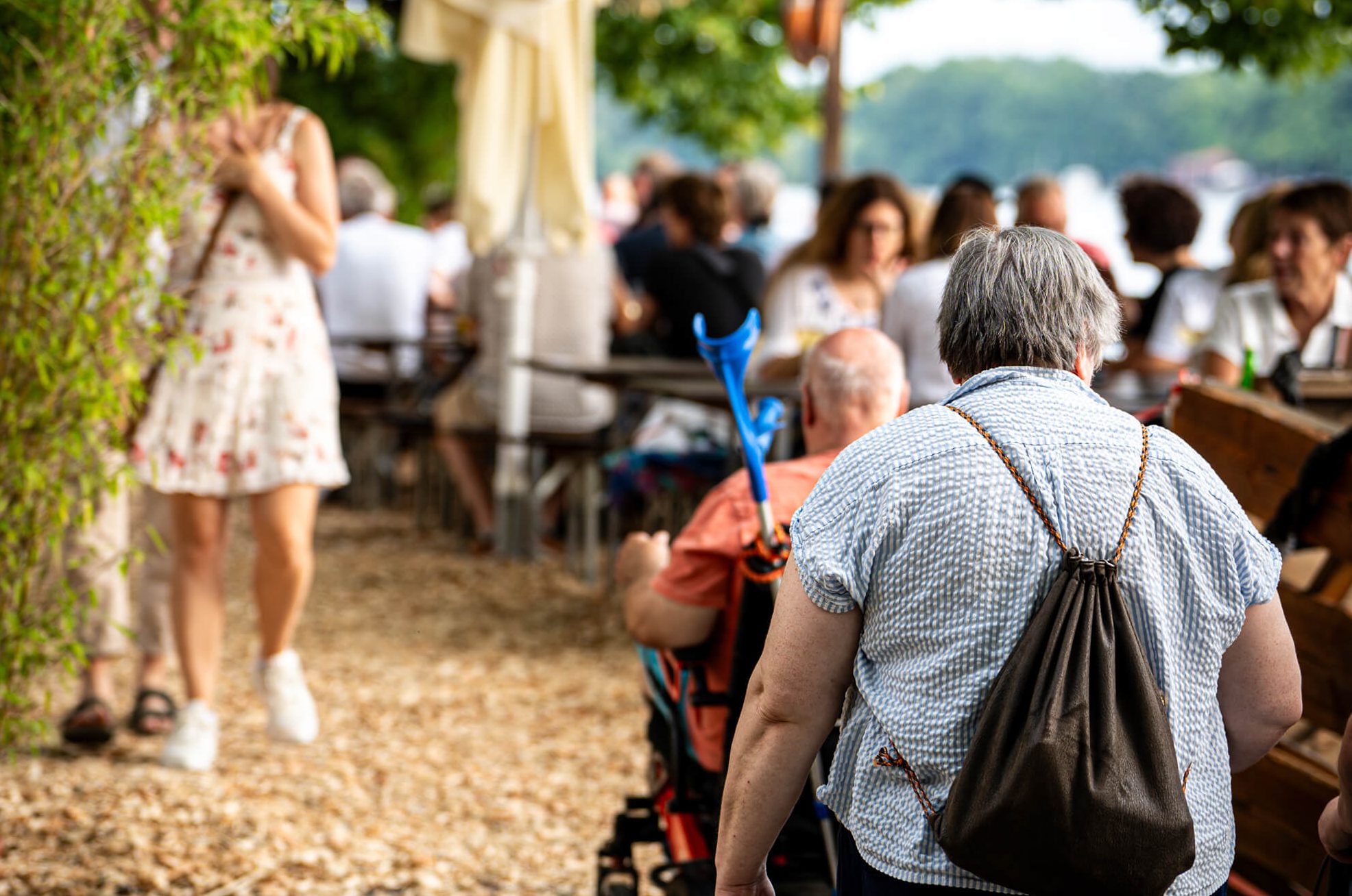 Eine ältere Person im Freien, umgeben von anderen Menschen