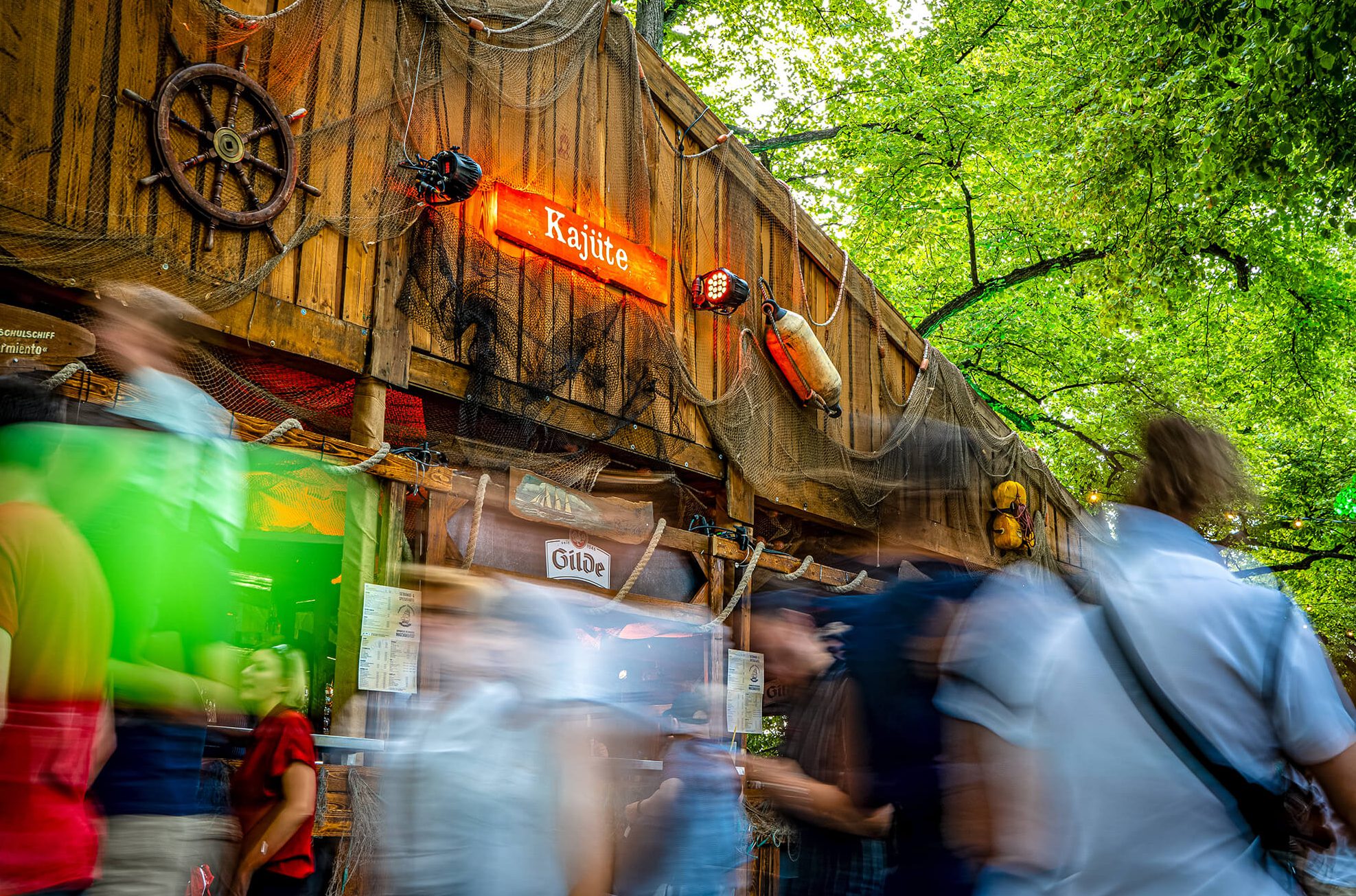 Menschen vor einem hölzernen Gebäude mit dem Schild "Kajüte"