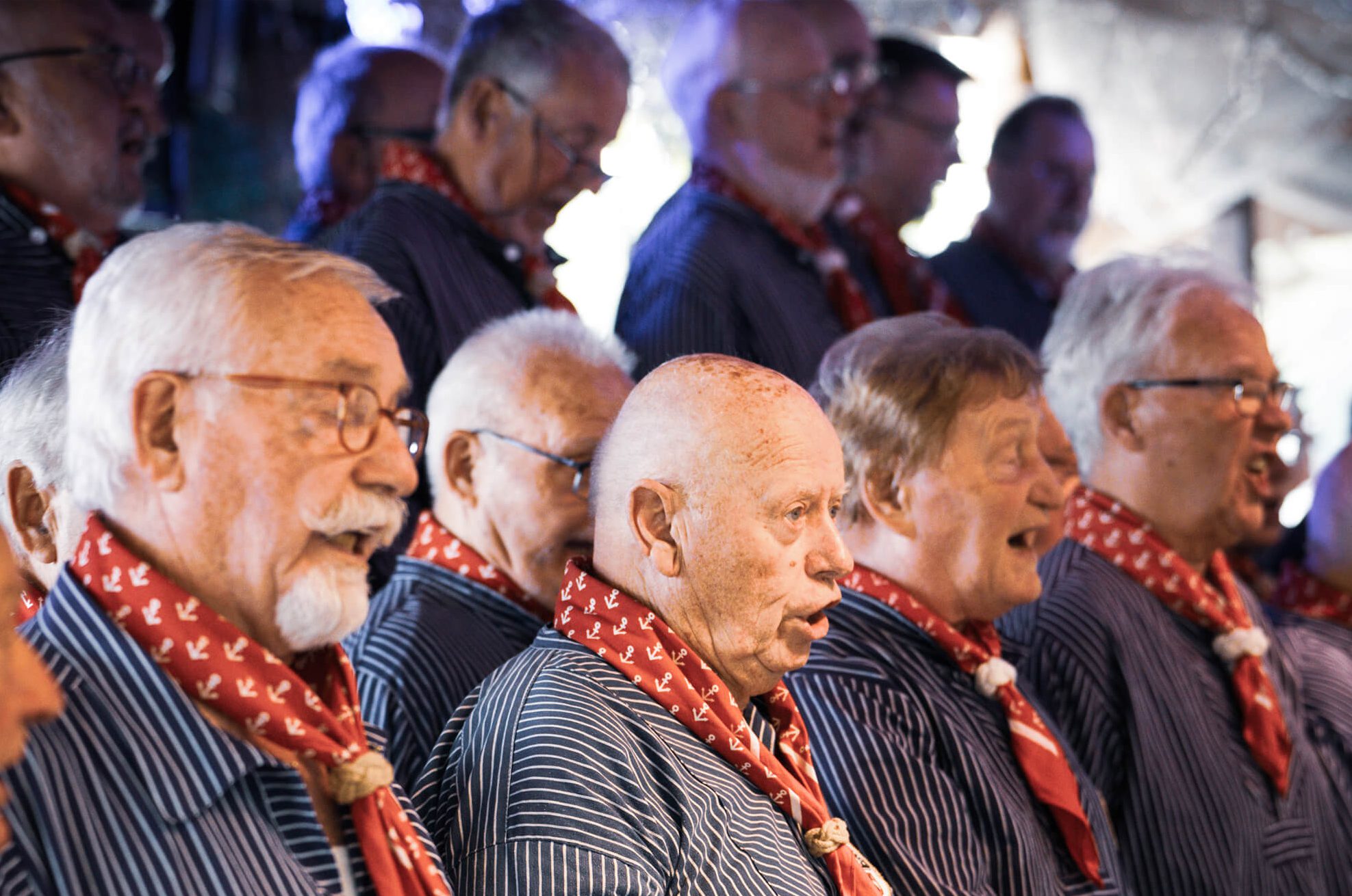 Chor von älteren Männern in gestreiften Hemden und roten Schals