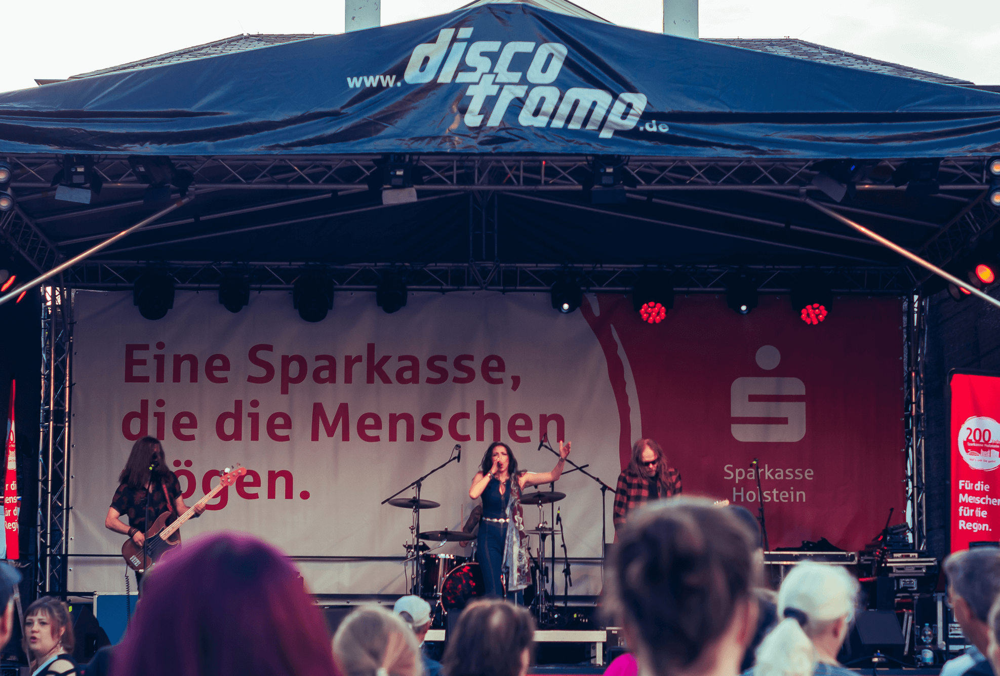 Eine Band tritt auf einer Bühne mit einem Sparkassen-Banner auf.