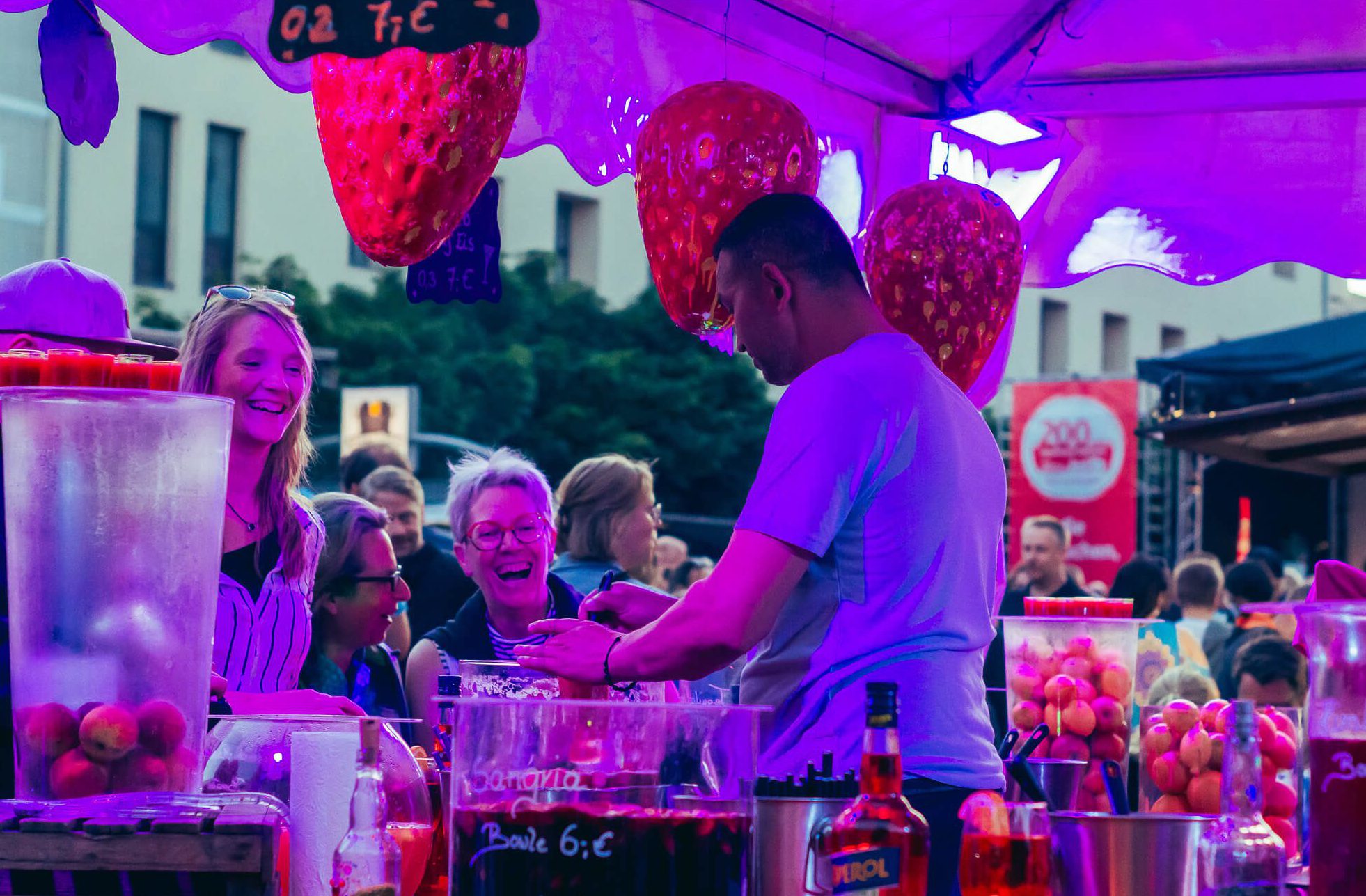 Menschen genießen Getränke an einem beleuchteten Getränkestand.